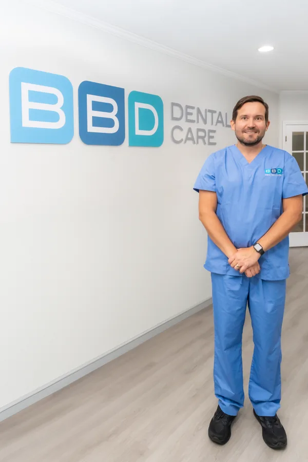 Integrante del equipo de BBD Dental Care junto al mural con el logo de la clínica
