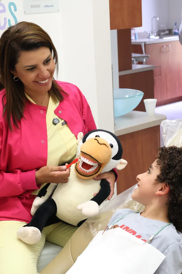 Odontóloga explicando la higiene dental a un paciente pediátrico