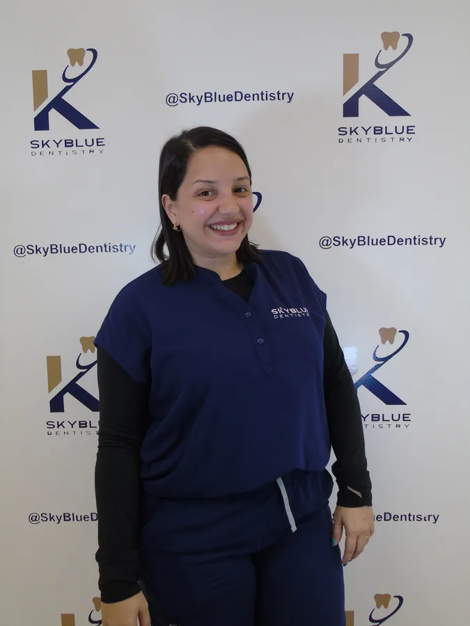Integrante del equipo de SkyBlue Dentistry frente al backdrop de marca
